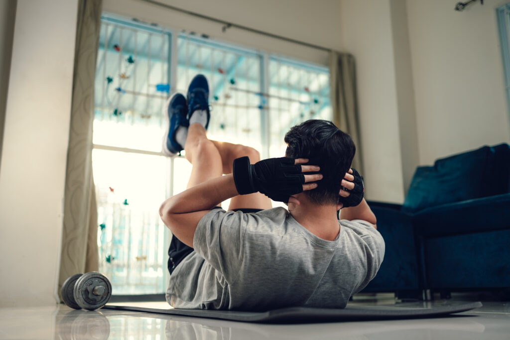 Man doing crunches on an exercise mat at home to rebuild core strength before returning to work after injury